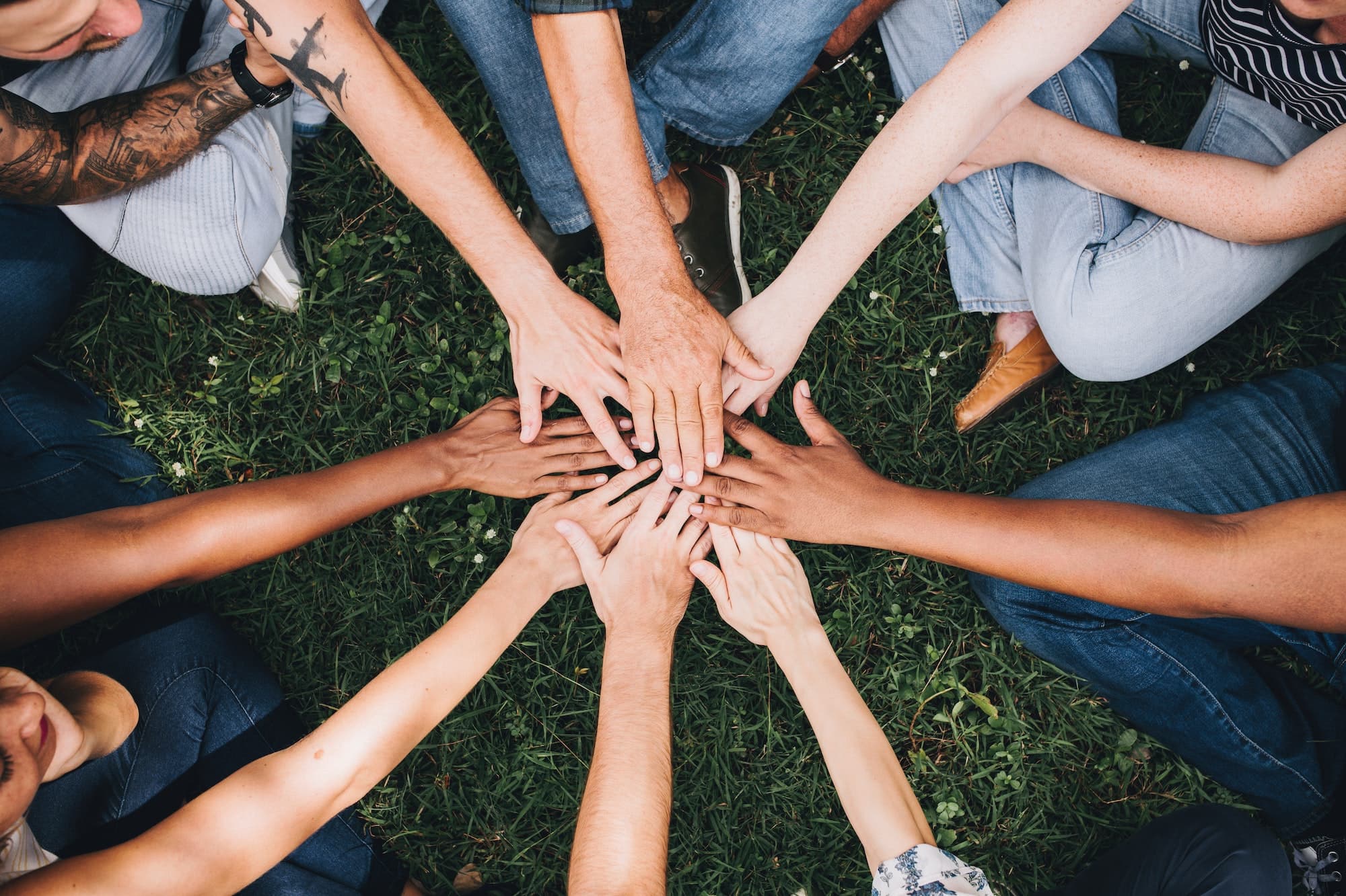 Diverse group of community members joining hands together in a circle